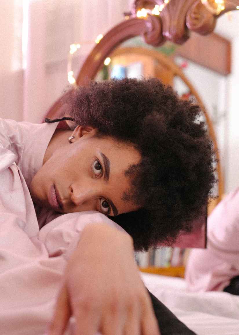 dreamy ethnic man in shirt lying on arms