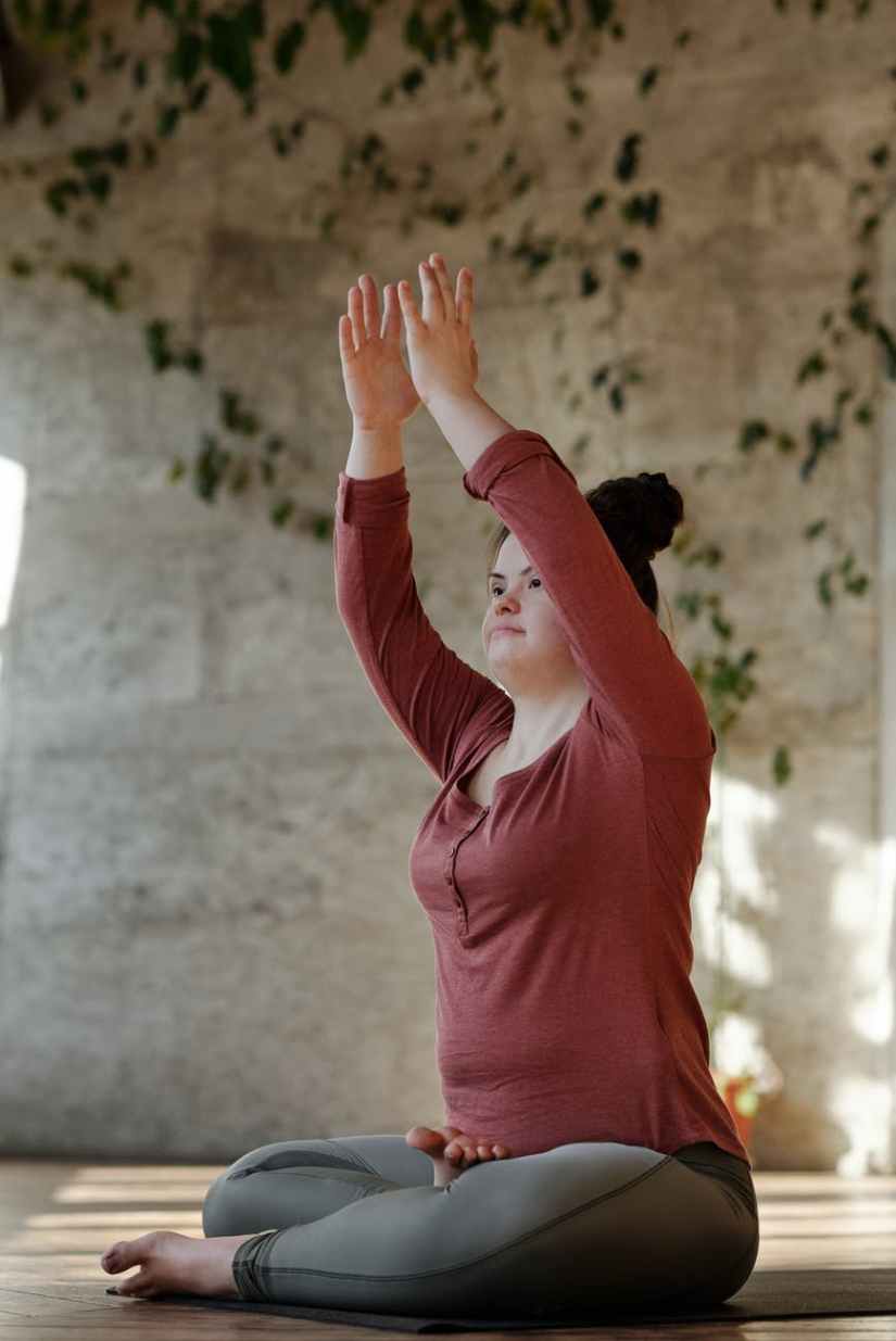 photo of young woman with her arms raised while in a sitting position